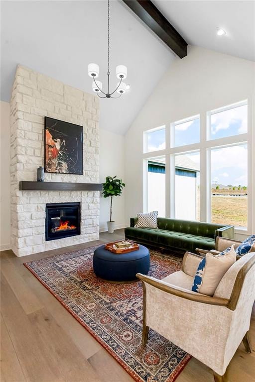 living room featuring wood-type flooring, plenty of natural light, a stone fireplace, and high vaulted ceiling