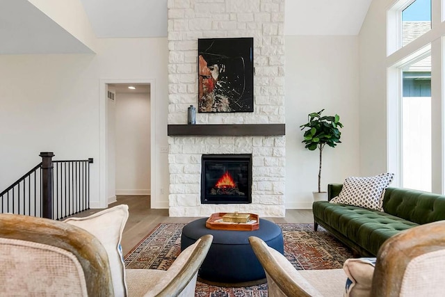 living room with vaulted ceiling, a fireplace, and hardwood / wood-style floors