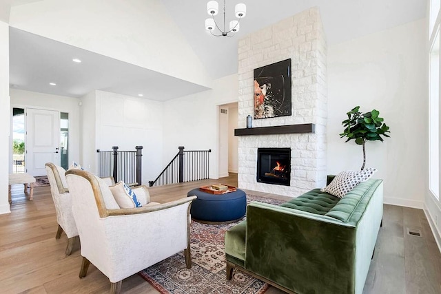 living room with wood-type flooring, a fireplace, high vaulted ceiling, and a notable chandelier