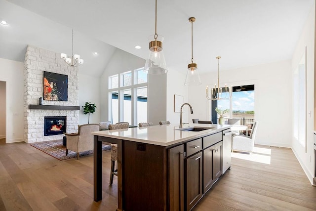 kitchen featuring pendant lighting, an island with sink, sink, and dark brown cabinets