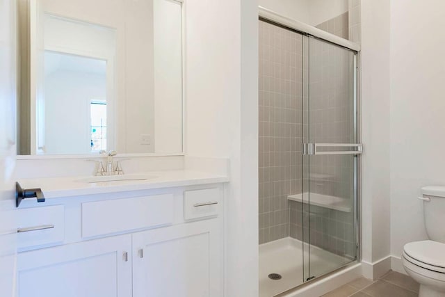 bathroom featuring vanity, a shower with shower door, tile patterned floors, and toilet