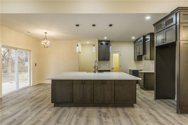 kitchen featuring pendant lighting, a kitchen island with sink, sink, and dark brown cabinetry