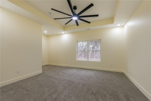 spare room featuring carpet floors, ceiling fan, and a tray ceiling