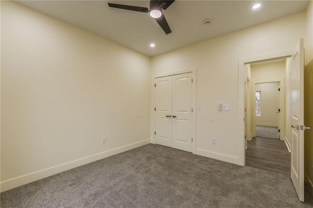 unfurnished bedroom with ceiling fan, dark carpet, and a closet