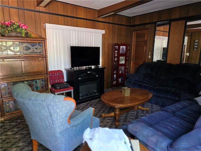 living room with beamed ceiling, carpet flooring, and wooden walls