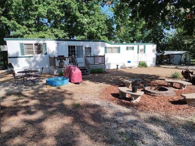 rear view of property with a wooden deck and an outdoor fire pit