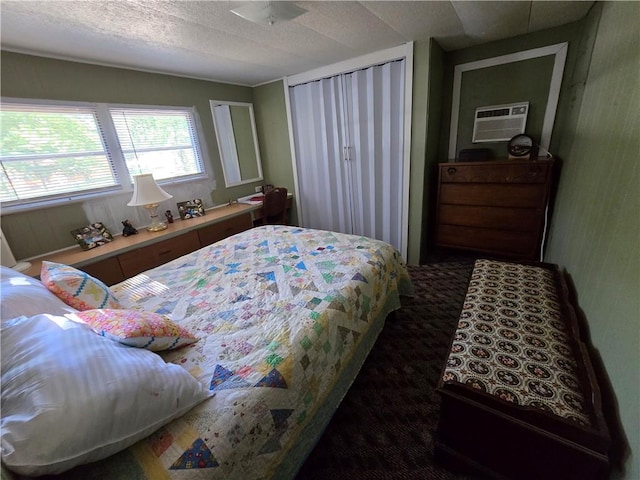 carpeted bedroom with a wall unit AC and a textured ceiling