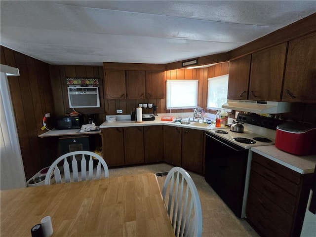 kitchen featuring dark brown cabinets, wooden walls, exhaust hood, electric stove, and sink