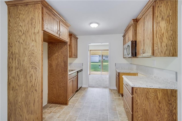 kitchen featuring baseboards, appliances with stainless steel finishes, brown cabinetry, and light stone counters