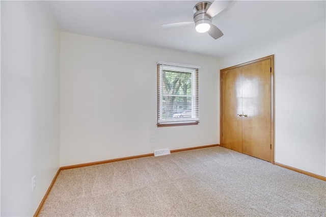 unfurnished room featuring a ceiling fan, visible vents, light carpet, and baseboards