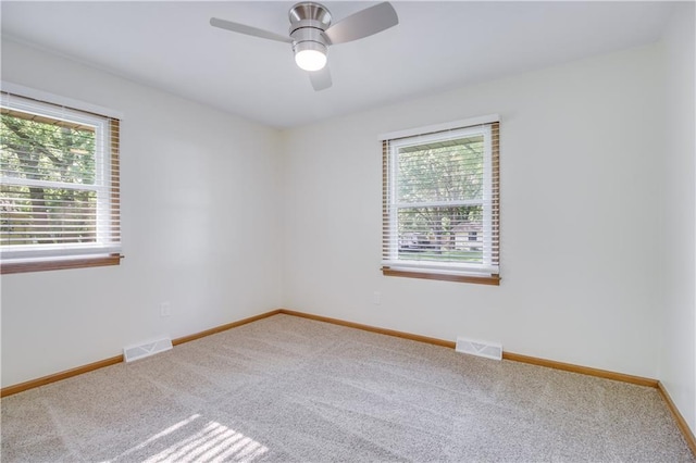 carpeted spare room featuring baseboards, visible vents, and a wealth of natural light