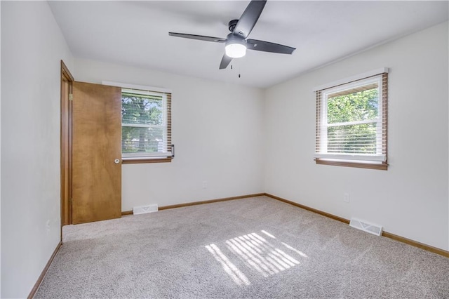 unfurnished room featuring a wealth of natural light, visible vents, and carpet flooring