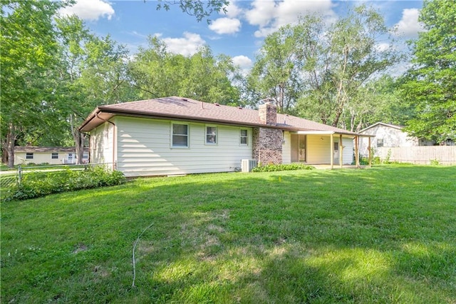 rear view of house featuring central AC, a yard, a chimney, and fence