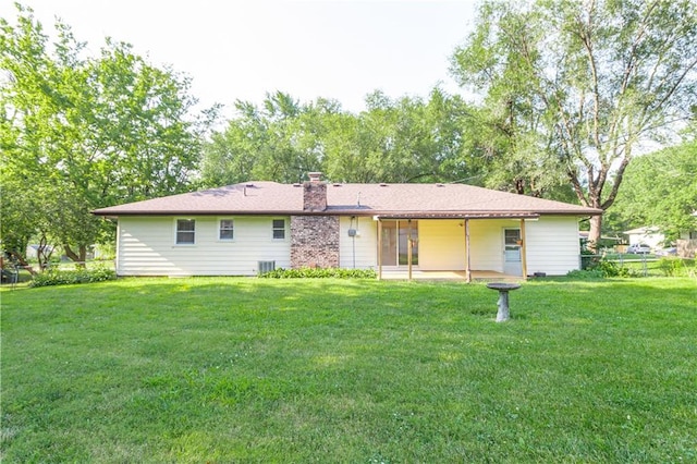 rear view of property featuring a lawn, a chimney, and cooling unit