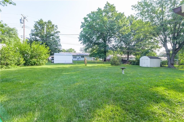 view of yard featuring a storage shed, fence, and an outbuilding