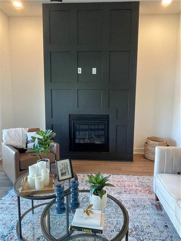 living area featuring baseboards, a large fireplace, and wood finished floors