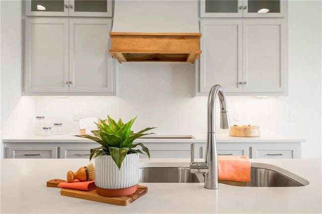 interior space with light countertops, glass insert cabinets, gray cabinets, and a sink