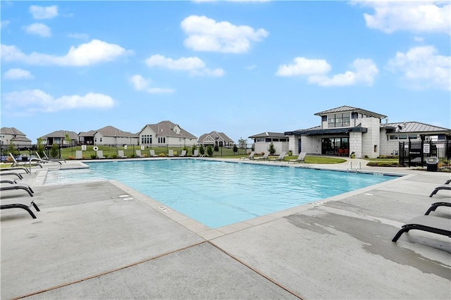 pool with a patio area, fence, and a residential view