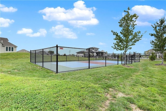 view of basketball court featuring a lawn and fence