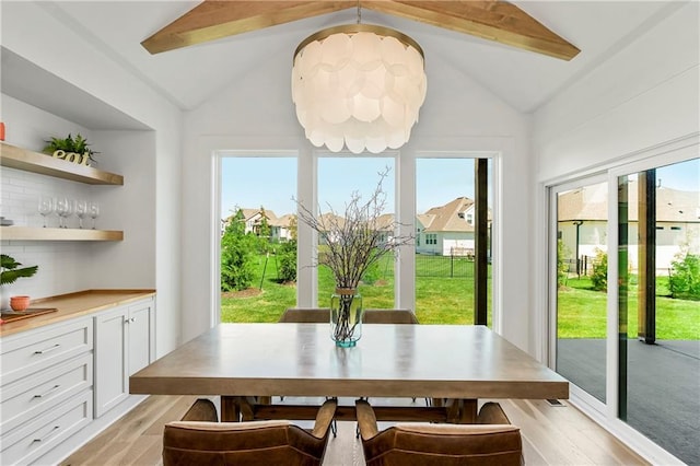 dining area featuring lofted ceiling with beams and light wood-type flooring