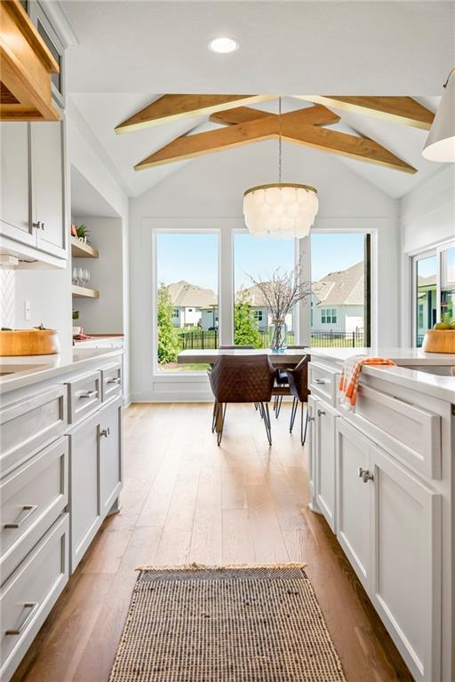 kitchen with light wood-style flooring, vaulted ceiling with beams, and a wealth of natural light