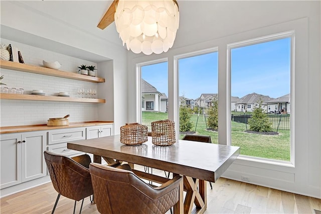 dining area featuring plenty of natural light, beamed ceiling, a residential view, and light wood-style floors