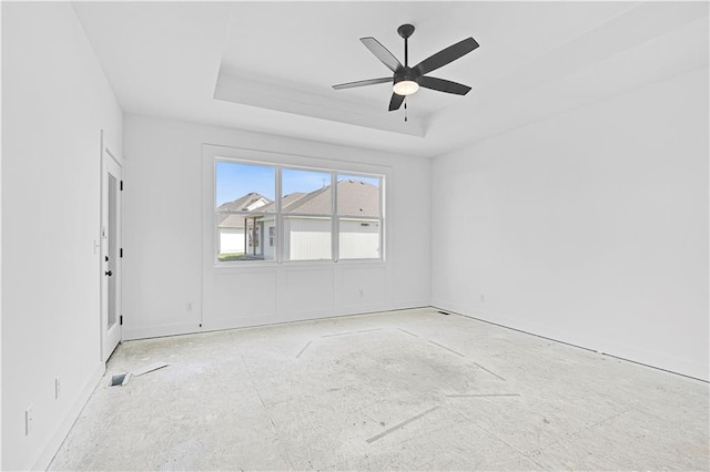 spare room with a raised ceiling, a ceiling fan, and visible vents