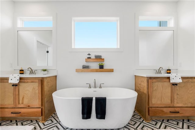 bathroom featuring a freestanding tub, two vanities, and a healthy amount of sunlight