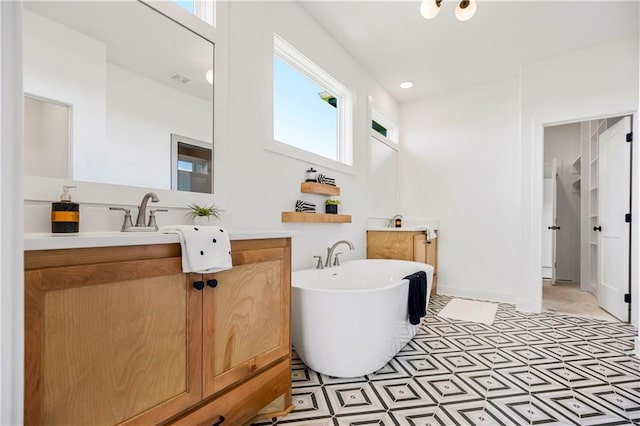 bathroom featuring a soaking tub, vanity, and baseboards