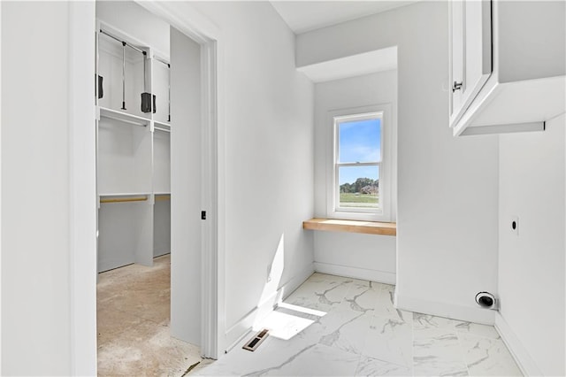 interior space with baseboards, hookup for an electric dryer, marble finish floor, and laundry area