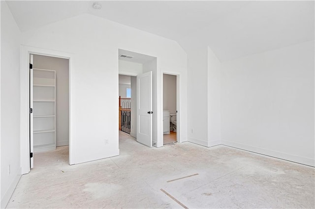 unfurnished bedroom with a spacious closet, visible vents, connected bathroom, and lofted ceiling