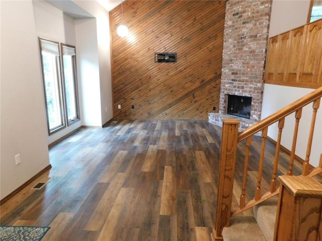 unfurnished living room with a fireplace, wooden walls, and dark hardwood / wood-style flooring