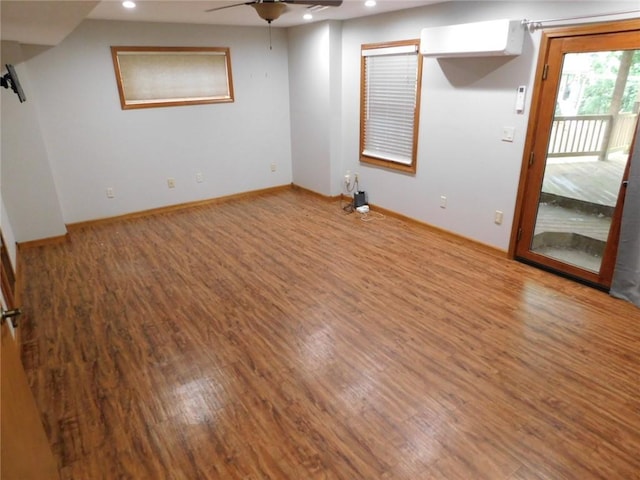 interior space featuring hardwood / wood-style flooring, an AC wall unit, and ceiling fan