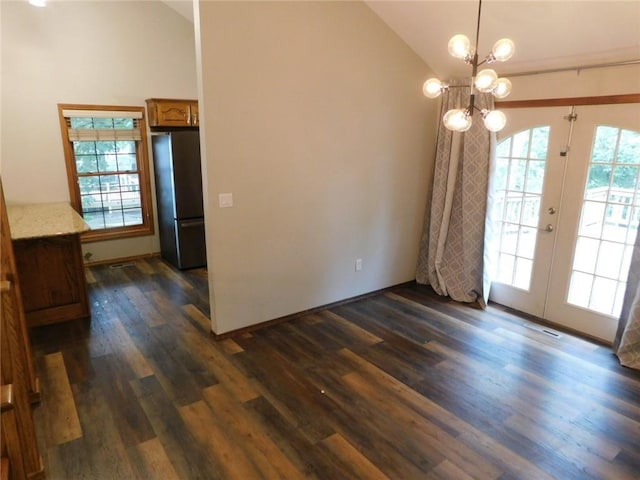 unfurnished dining area with dark hardwood / wood-style flooring, high vaulted ceiling, french doors, and a chandelier