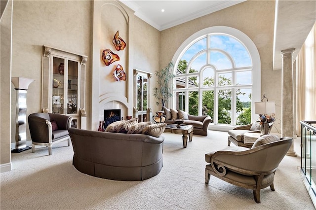 carpeted living room with a high ceiling, crown molding, and decorative columns