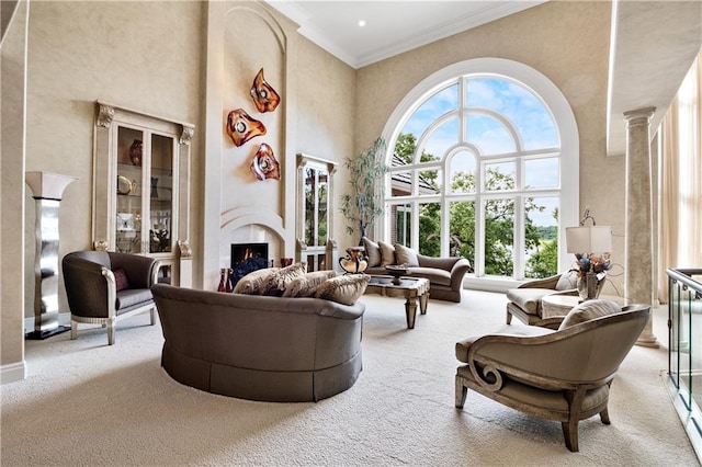 living room featuring a towering ceiling, a lit fireplace, crown molding, and carpet floors