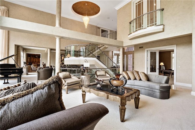 carpeted living room with decorative columns, crown molding, and a towering ceiling