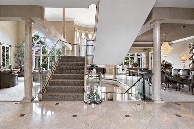 stairs featuring crown molding, tile patterned flooring, ornate columns, and a healthy amount of sunlight