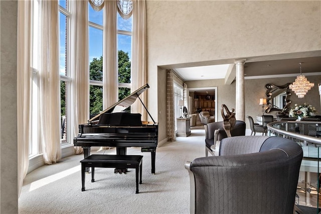 living area featuring baseboards, an inviting chandelier, a towering ceiling, and carpet