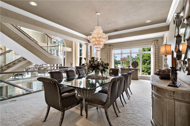 dining area featuring a raised ceiling, an inviting chandelier, light colored carpet, and stairway