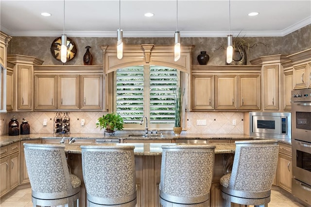 kitchen with a sink, appliances with stainless steel finishes, a kitchen breakfast bar, an island with sink, and decorative backsplash
