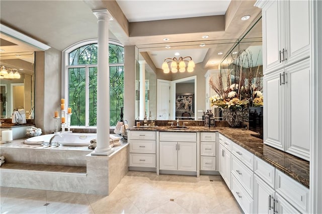 bathroom featuring decorative columns, tile patterned floors, vanity, tiled tub, and a raised ceiling