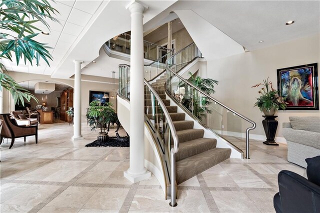 staircase with ornate columns, baseboards, an AC wall unit, and arched walkways