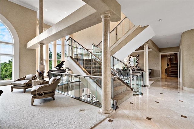 stairway with light carpet, decorative columns, and a high ceiling