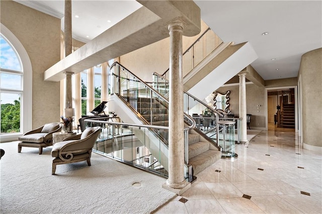 stairs with ornate columns, a towering ceiling, and recessed lighting