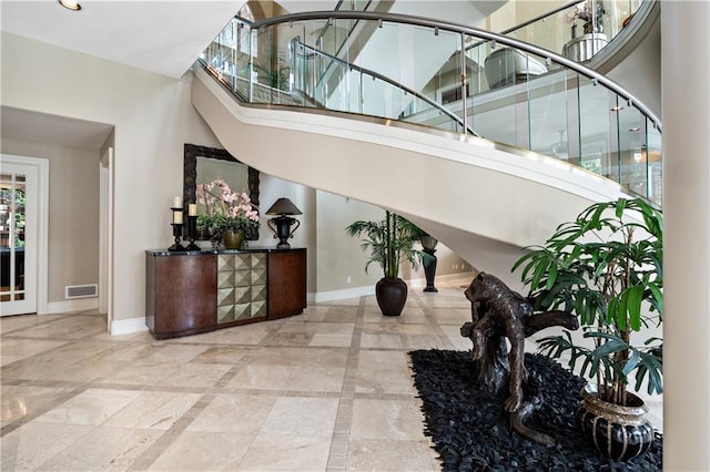 foyer entrance featuring visible vents, baseboards, and stairway