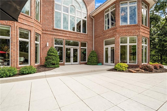 back of property featuring brick siding and french doors