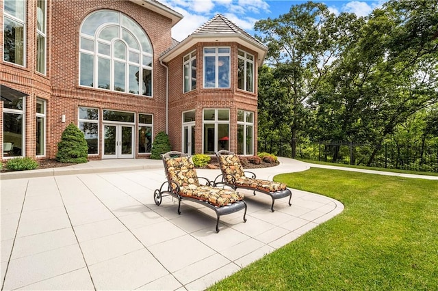 rear view of house with a patio, french doors, brick siding, and a lawn
