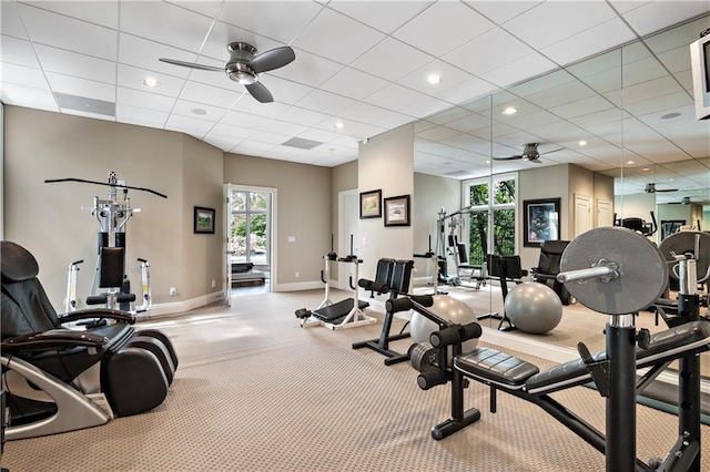 gym with a paneled ceiling, carpet flooring, baseboards, and a ceiling fan