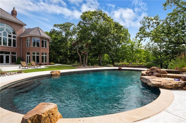 outdoor pool featuring french doors and a patio